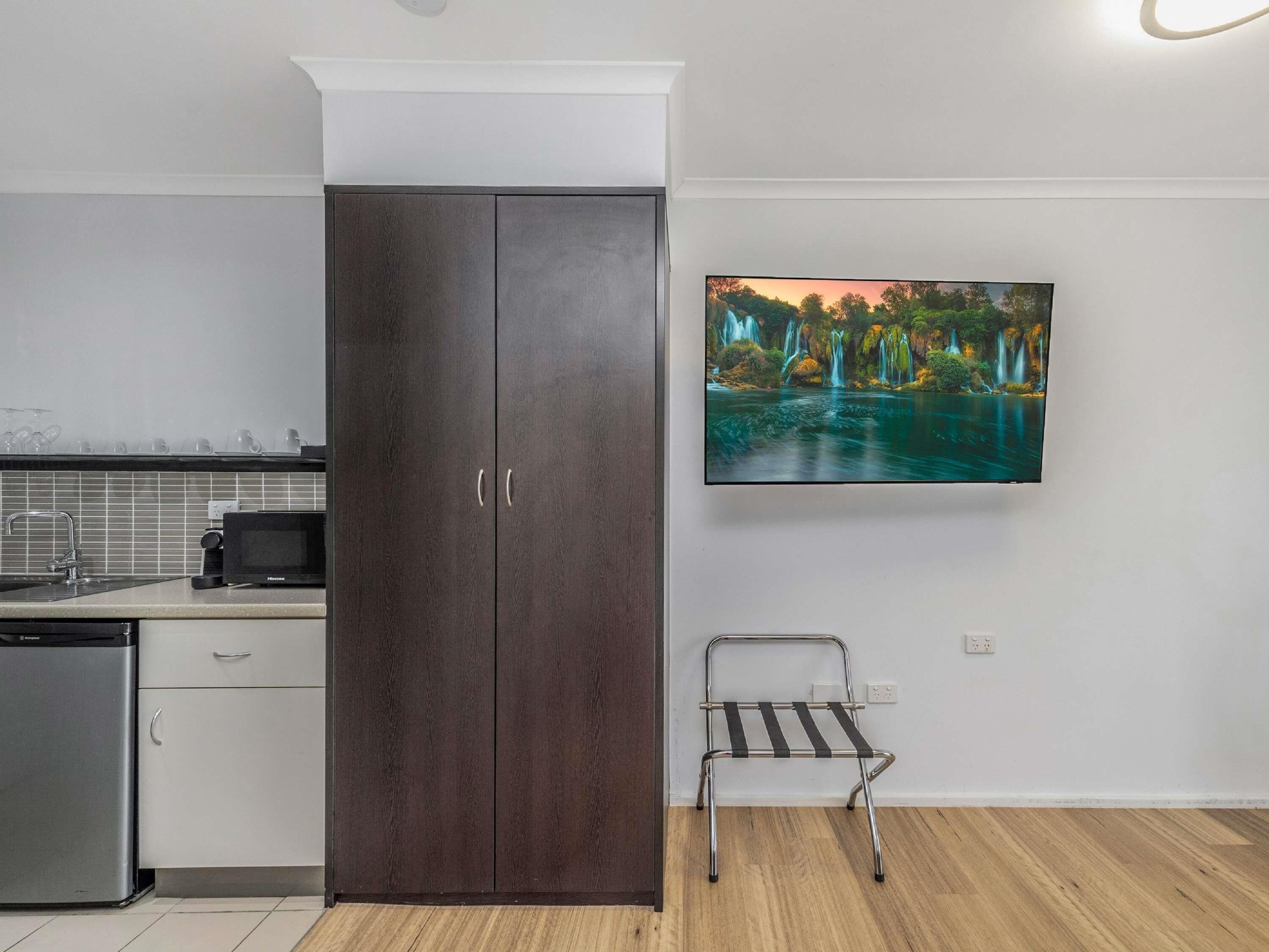 A modern kitchen with a dark wood cabinet, a microwave, and a sink.