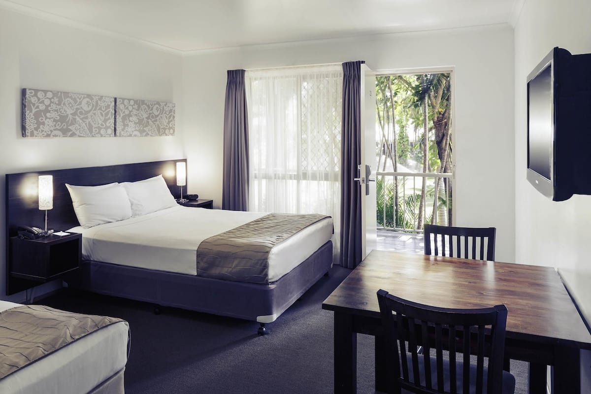Une chambre d’hôtel comprenant un lit, une table de chevet, une lampe, une chaise et un téléviseur.