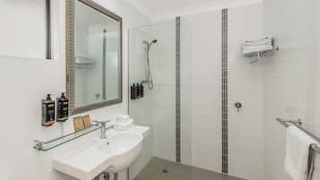 A modern bathroom with a glass shower enclosure, a white sink, and a large mirror.