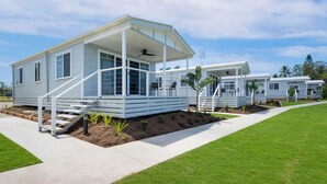 Una casa móvil moderna con un porche cubierto, un pequeño espacio de estar al aire libre y un césped bien cuidado.