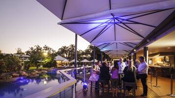 A poolside bar area with umbrellas, a pool, and lounge chairs.
