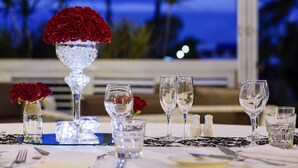 Una mesa lista para comer con vista despejada al océano y palmeras al fondo.