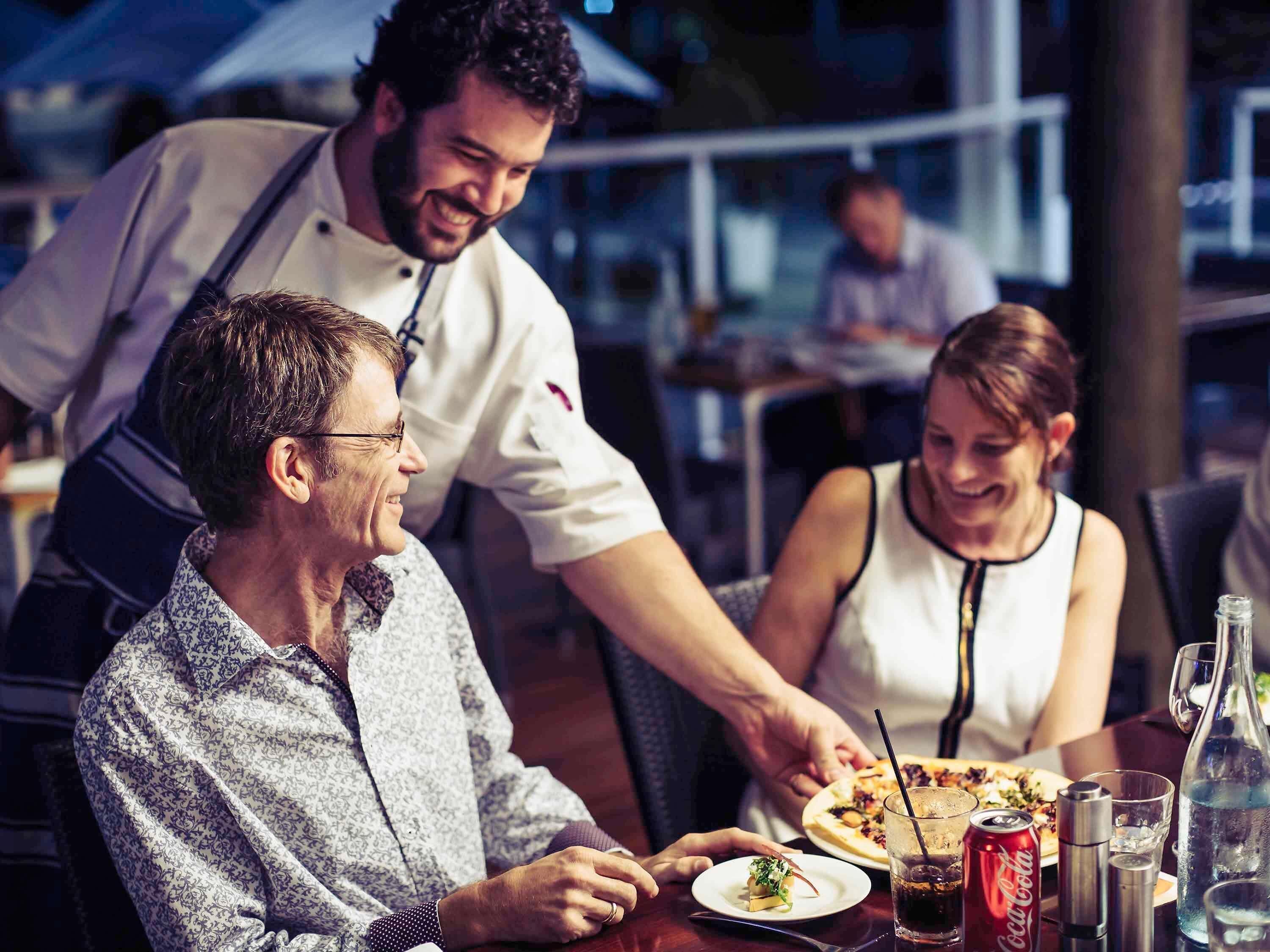 A restaurant setting with a waiter serving food to a table.