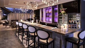 Een moderne bar met een lange toonbank, barstoelen en een wijnrek.