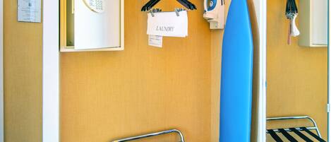 A laundry room with a wall-mounted dryer, ironing board, and ironing station.