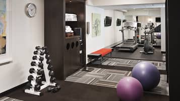 Een sportschool met trainingsapparatuur, een klok en een bank.