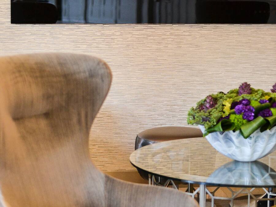 A modern living room with a comfortable armchair, a glass coffee table, and a decorative bowl with flowers.