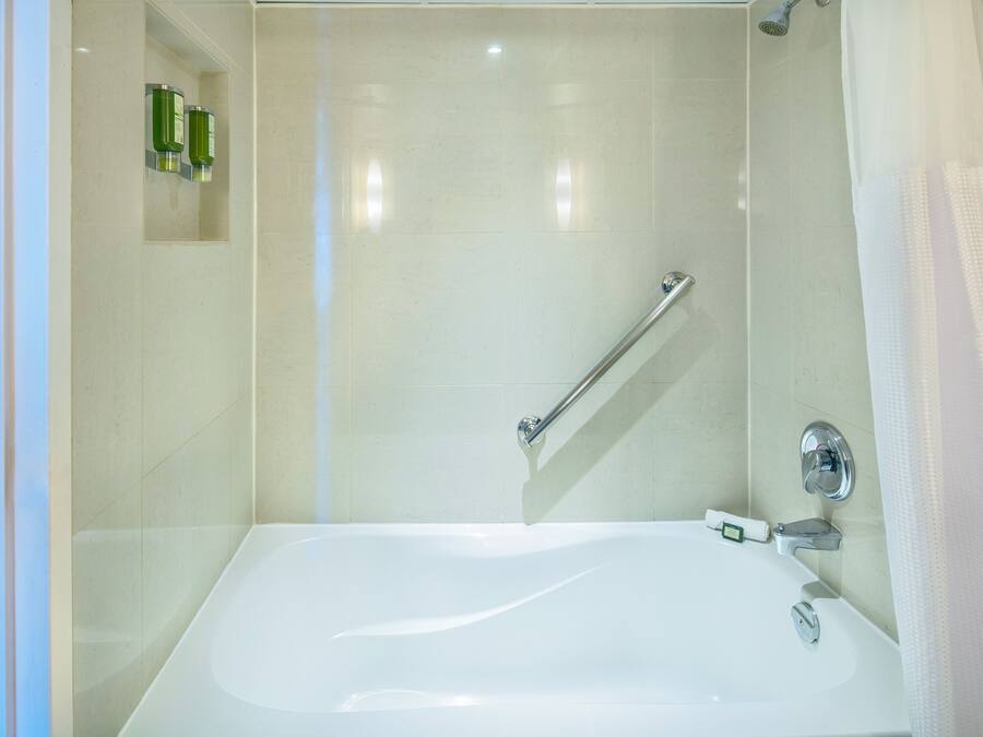 Uma casa de banho moderna com banheira, chuveiro e barra de apoio.