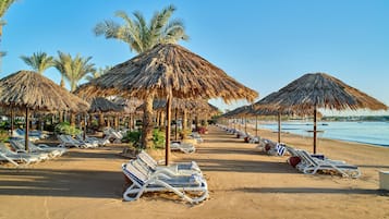 På stranden, solsenger, parasoller og strandhåndklær