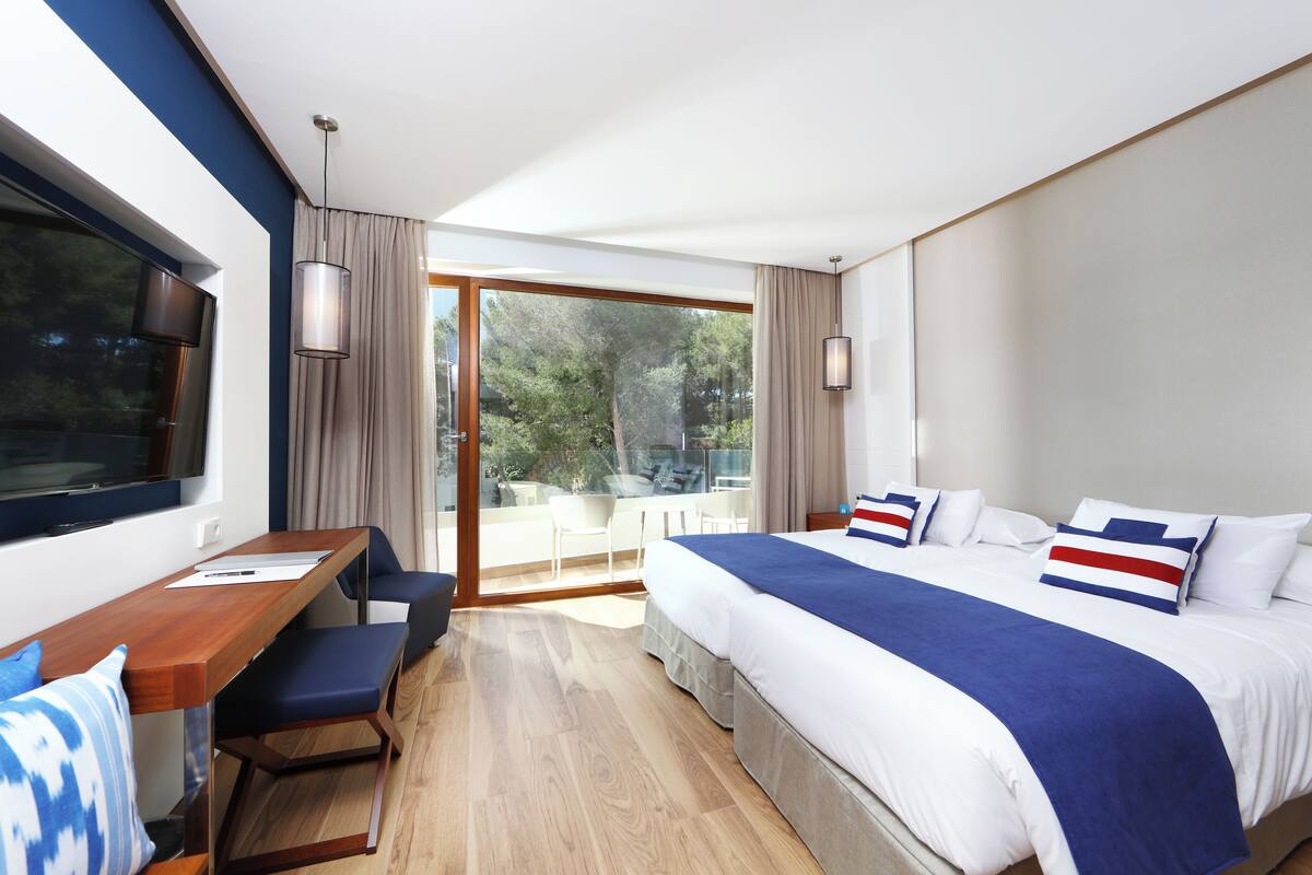 Een moderne hotelkamer met een groot bed, een bureau en uitzicht op de omgeving.