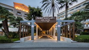Hotel Son Caliu SPA OASIS entrance with a modern design, palm trees, and a well-lit pathway. - Hotel Son Caliu Spa Oasis (Calvia)