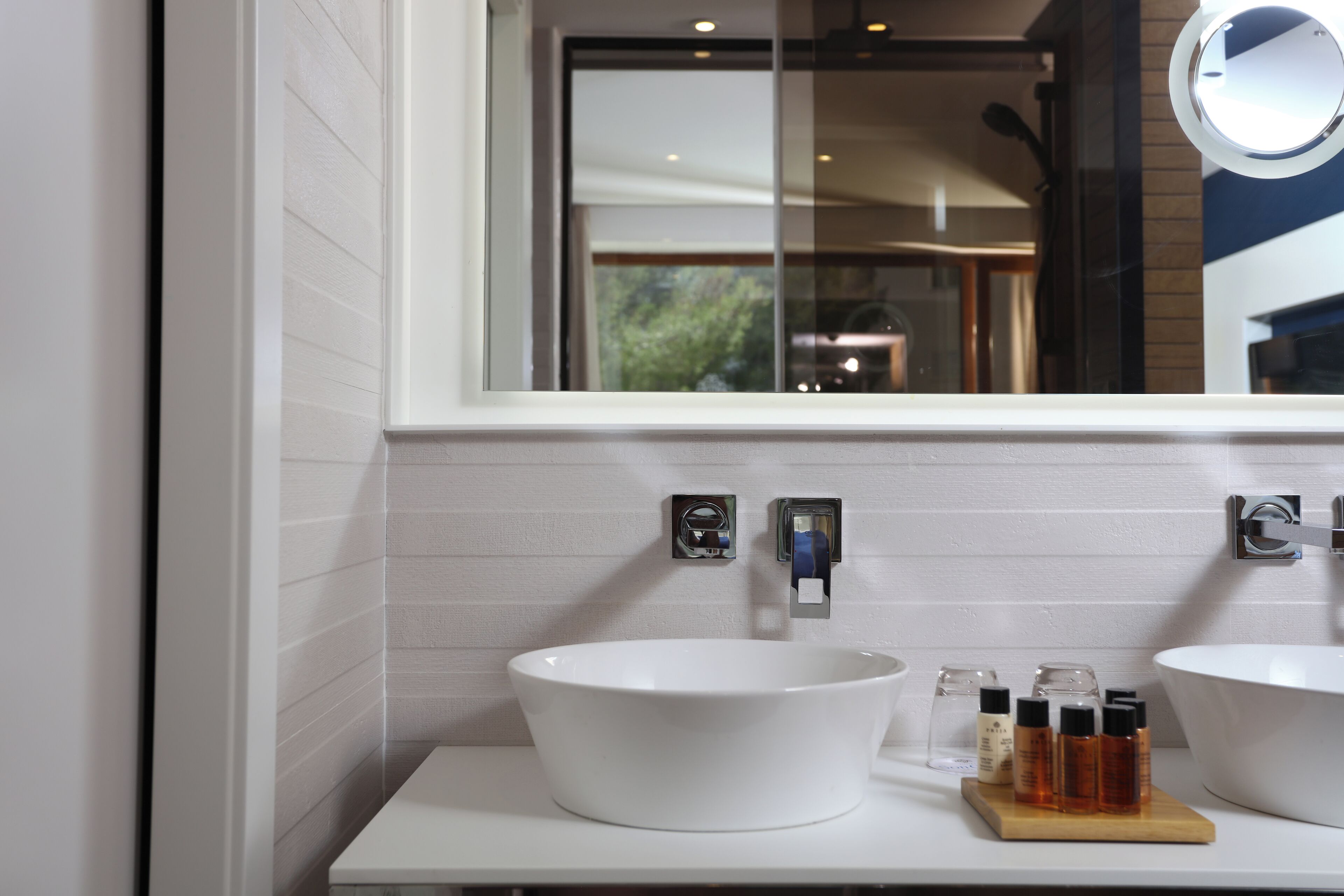 A bathroom with two white sinks, a window, and a mirror.