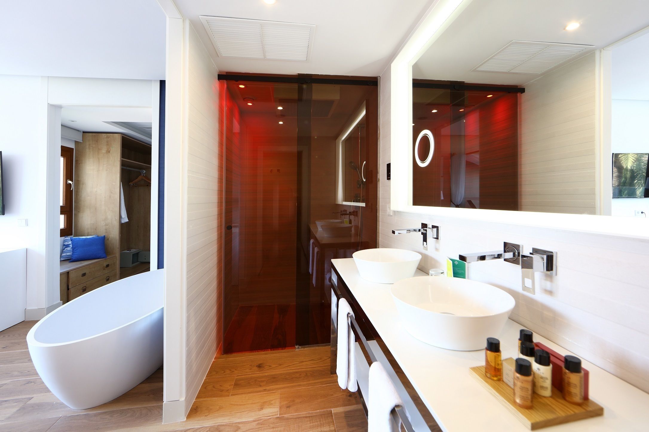Un baño moderno con una bañera independiente, dos lavabos y un espejo grande.