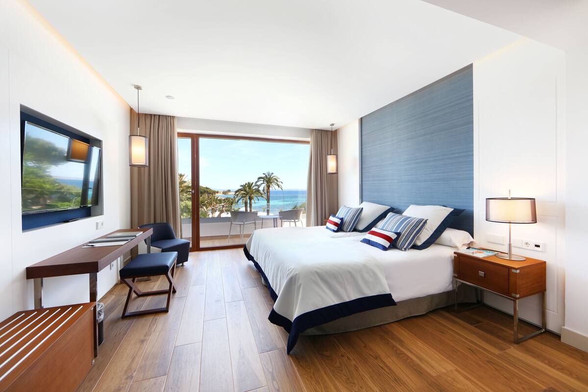 Een moderne hotelkamer met een groot bed, een bureau en uitzicht op de oceaan.