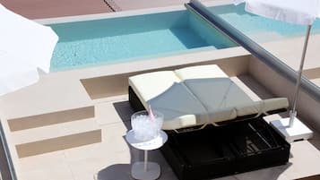 Ein Pool-Lounge-Bereich mit Liege, einem Getränk im Glas und einer Champagnerflasche.
