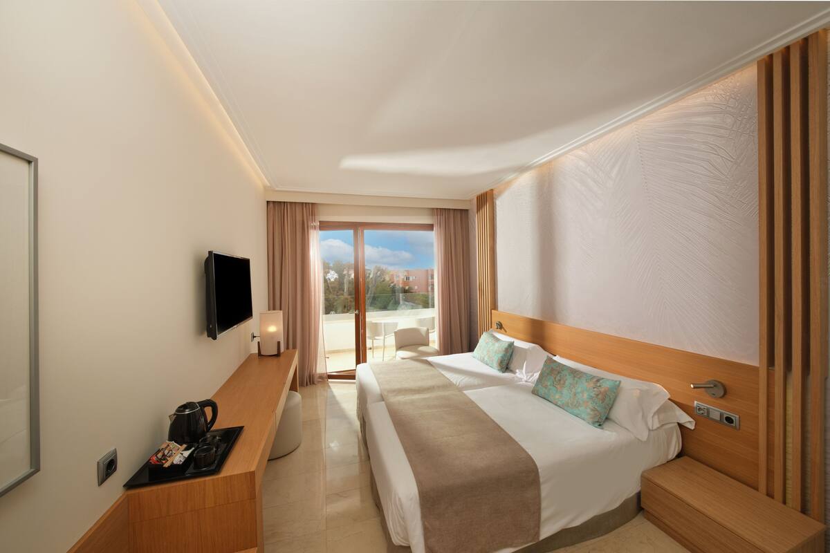 Een hotelkamer met een groot bed, een bureau met koffiezetapparaat, een televisie en uitzicht op de omgeving.