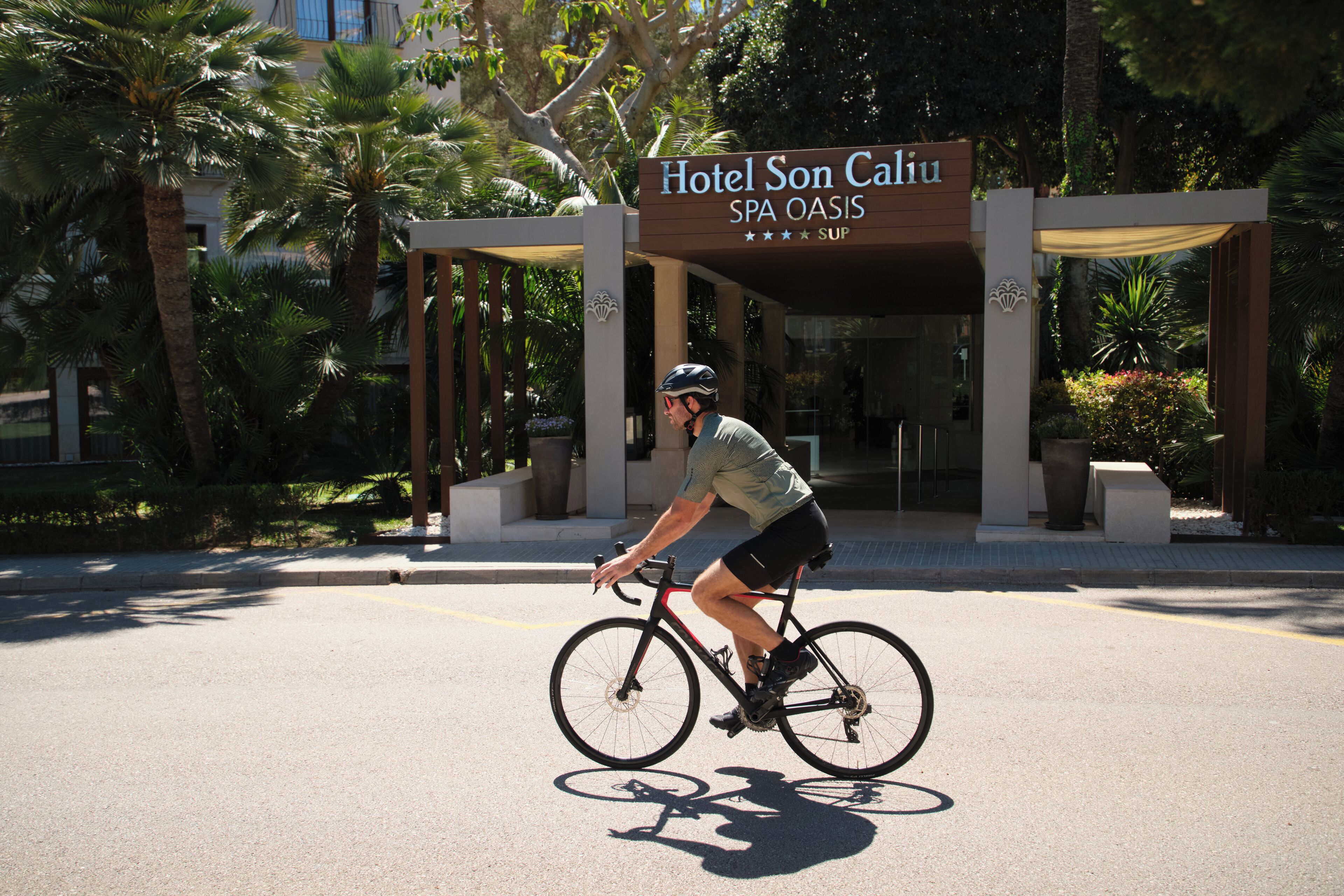 A cyclist riding past Hotel Son Caiu SPA OASIS.