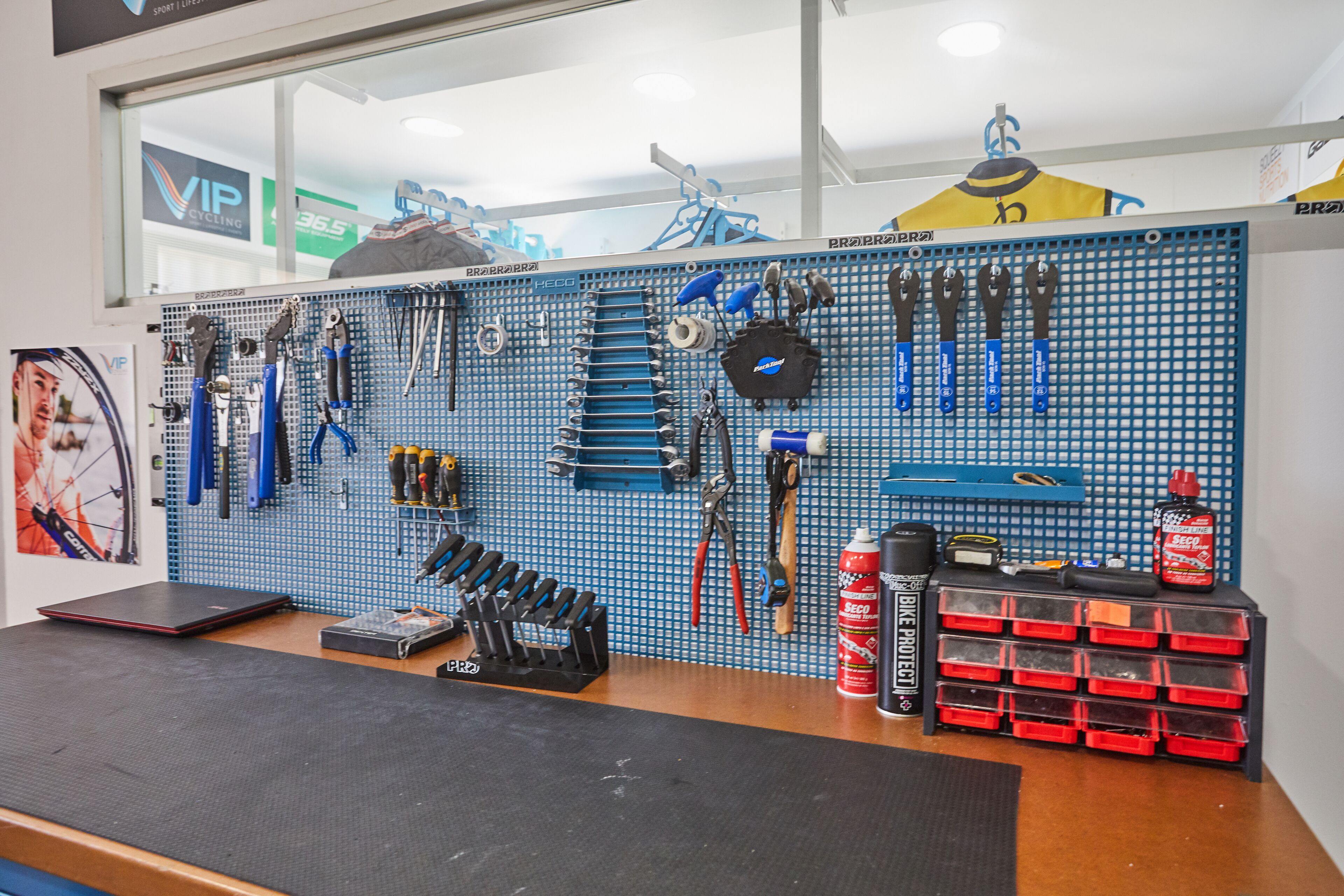 A workshop with tools and equipment on pegboards, a bike repair stand, and storage bins.