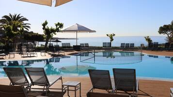 Een binnenzwembad, een buitenzwembad en parasols bij het zwembad