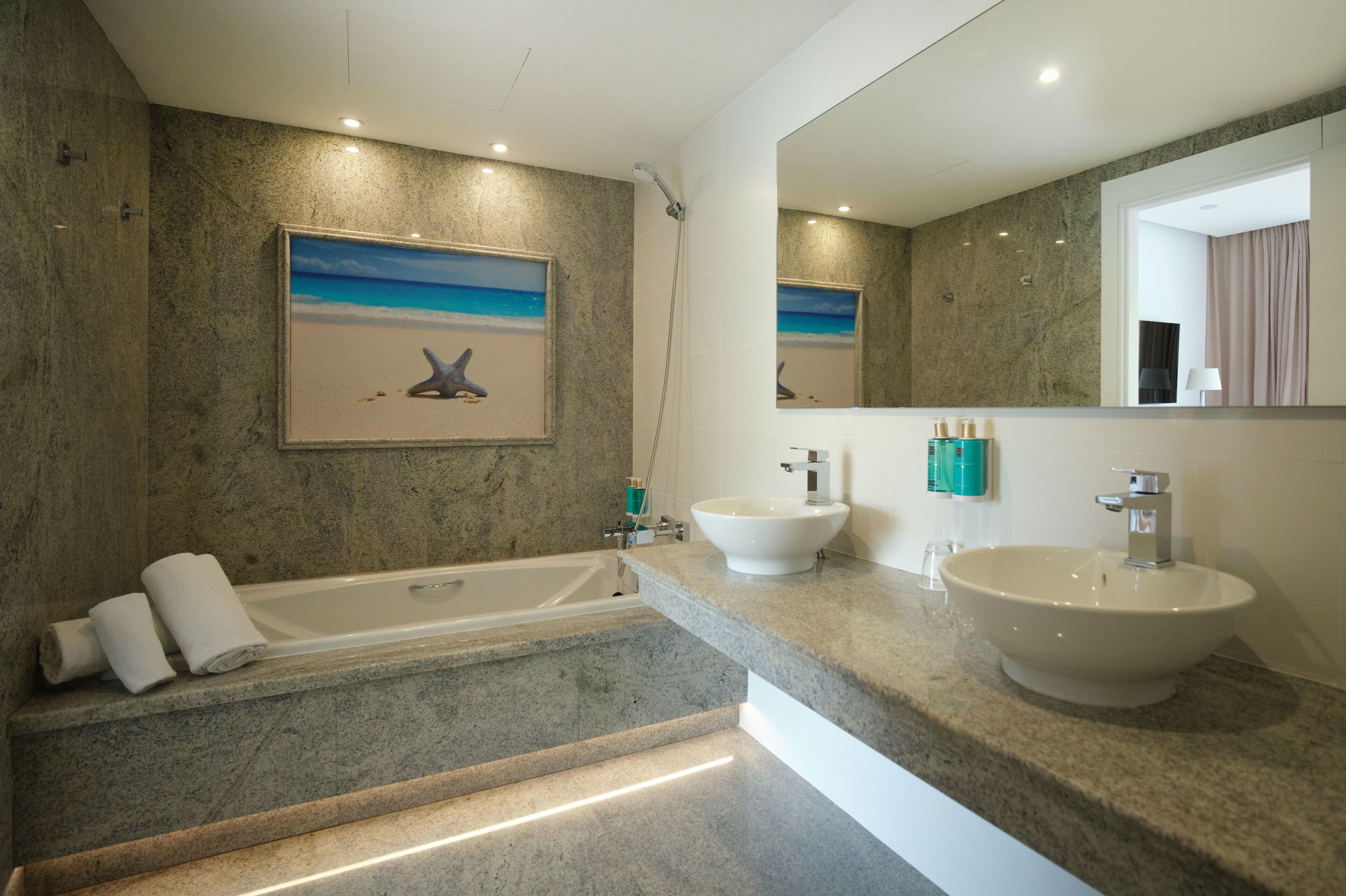 Un bagno moderno con una vasca, due lavandini e un grande specchio.