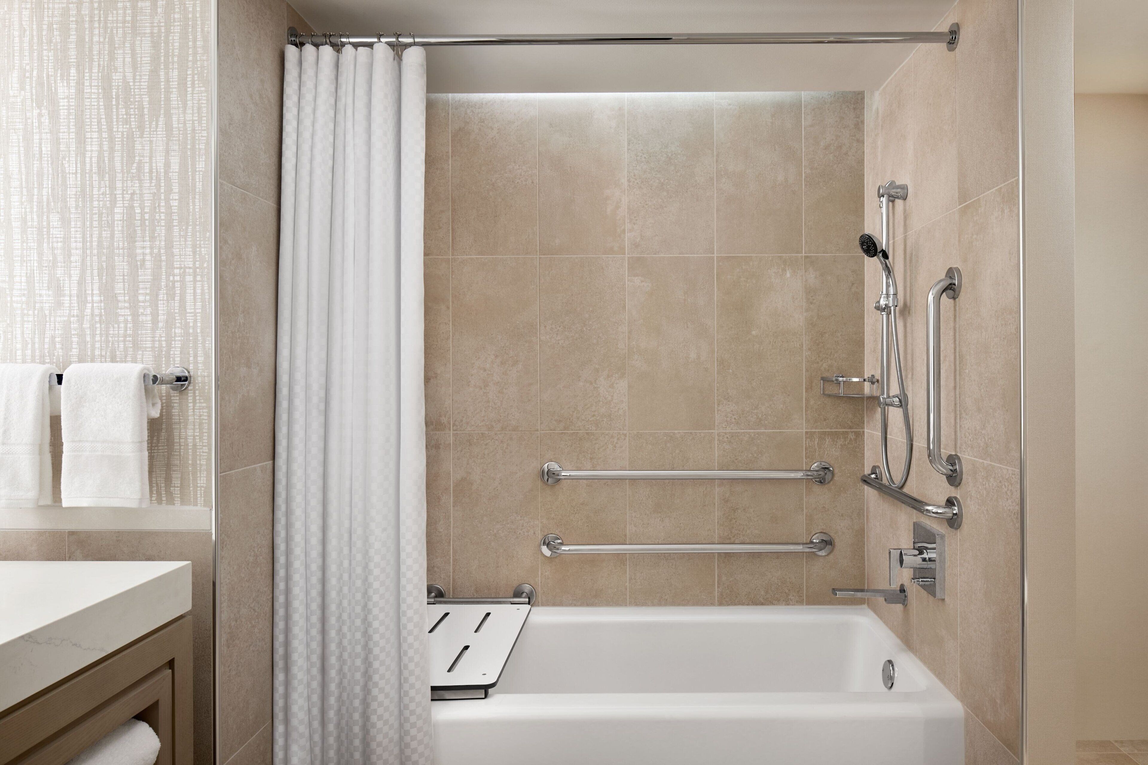 A modern bathroom with a bathtub, grab bars, and a shower curtain.