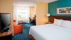 Une chambre d’hôtel avec un lit, une télévision, un bureau et une fenêtre avec des rideaux.