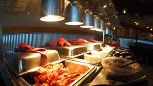 A buffet setup with various food items and serving utensils. - Evergreen Resort (Cadillac)