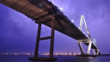 A large bridge with a steel structure and cables, spanning over water.