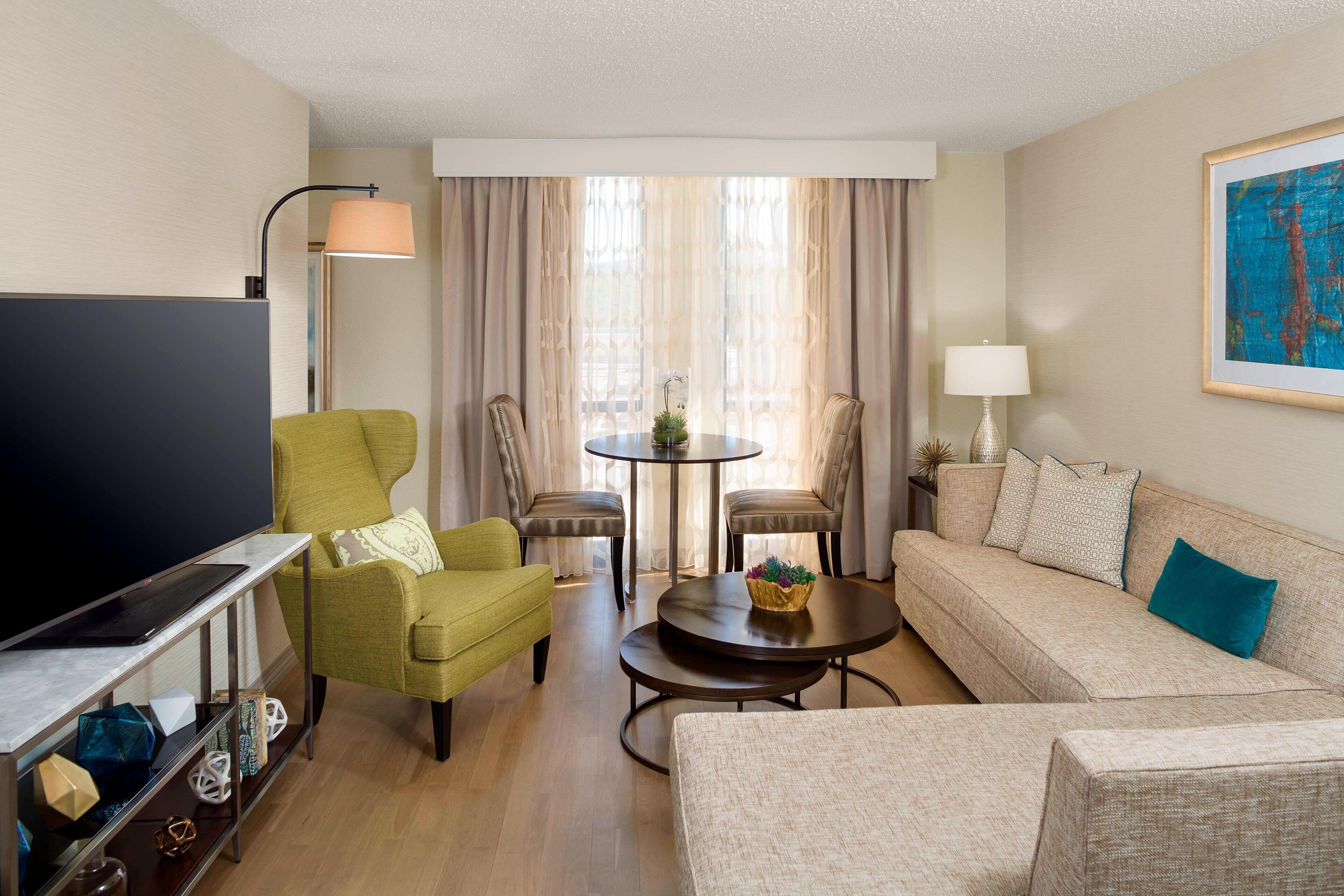 A living room with a sofa, two armchairs, a coffee table, a TV, and a lamp.