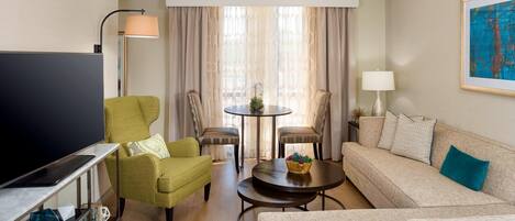 A living room with a sofa, two armchairs, a coffee table, a TV, and a lamp.