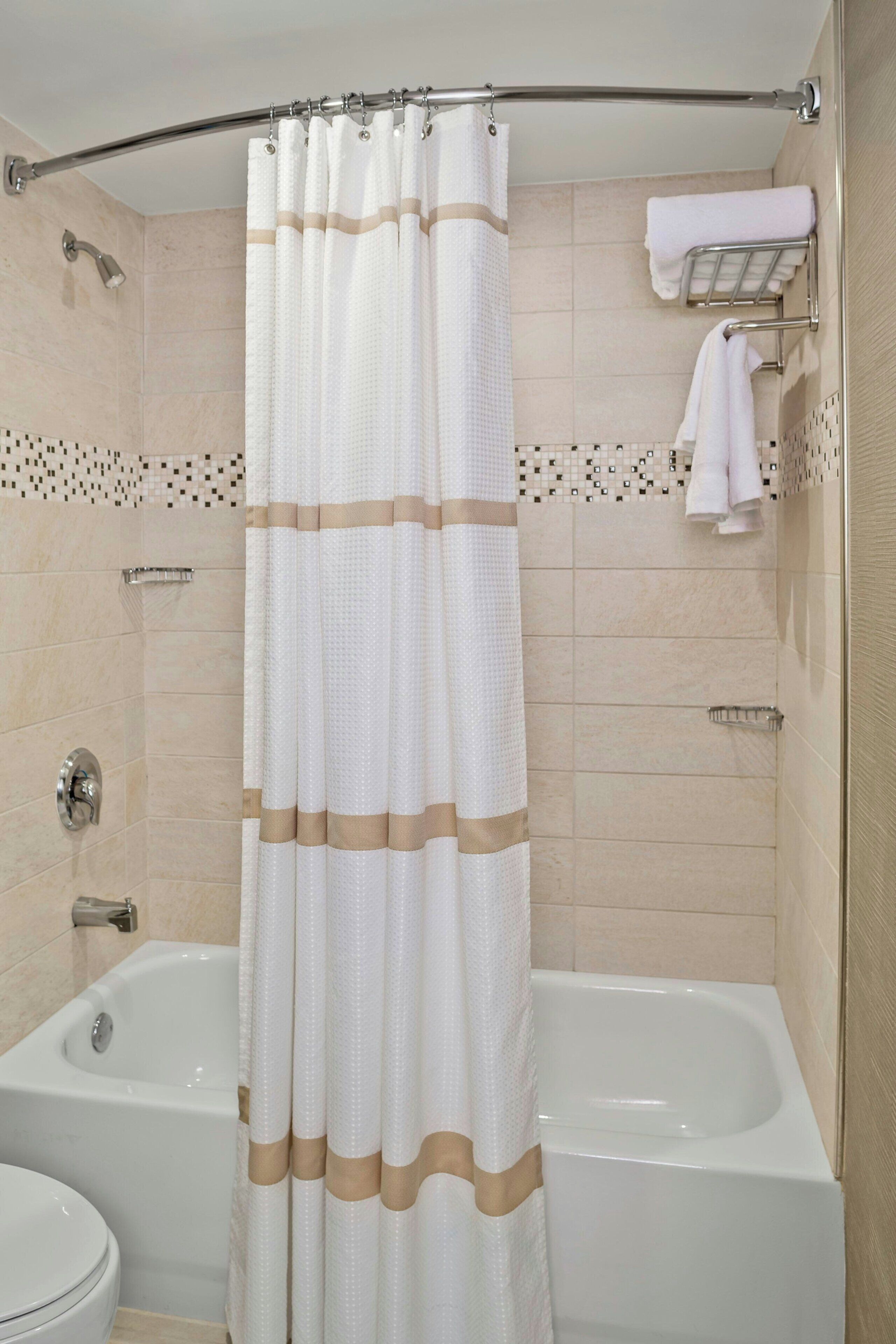 A bathroom with a bathtub, a toilet, and a shower curtain.