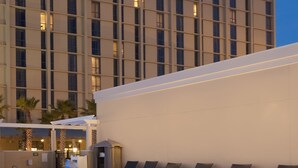 Un hotel Marriott con piscina, sillas de descanso y una zona cubierta.