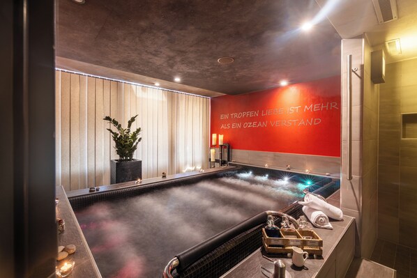 A spa room with a hot tub, a wall with a motivational quote, and a potted plant.