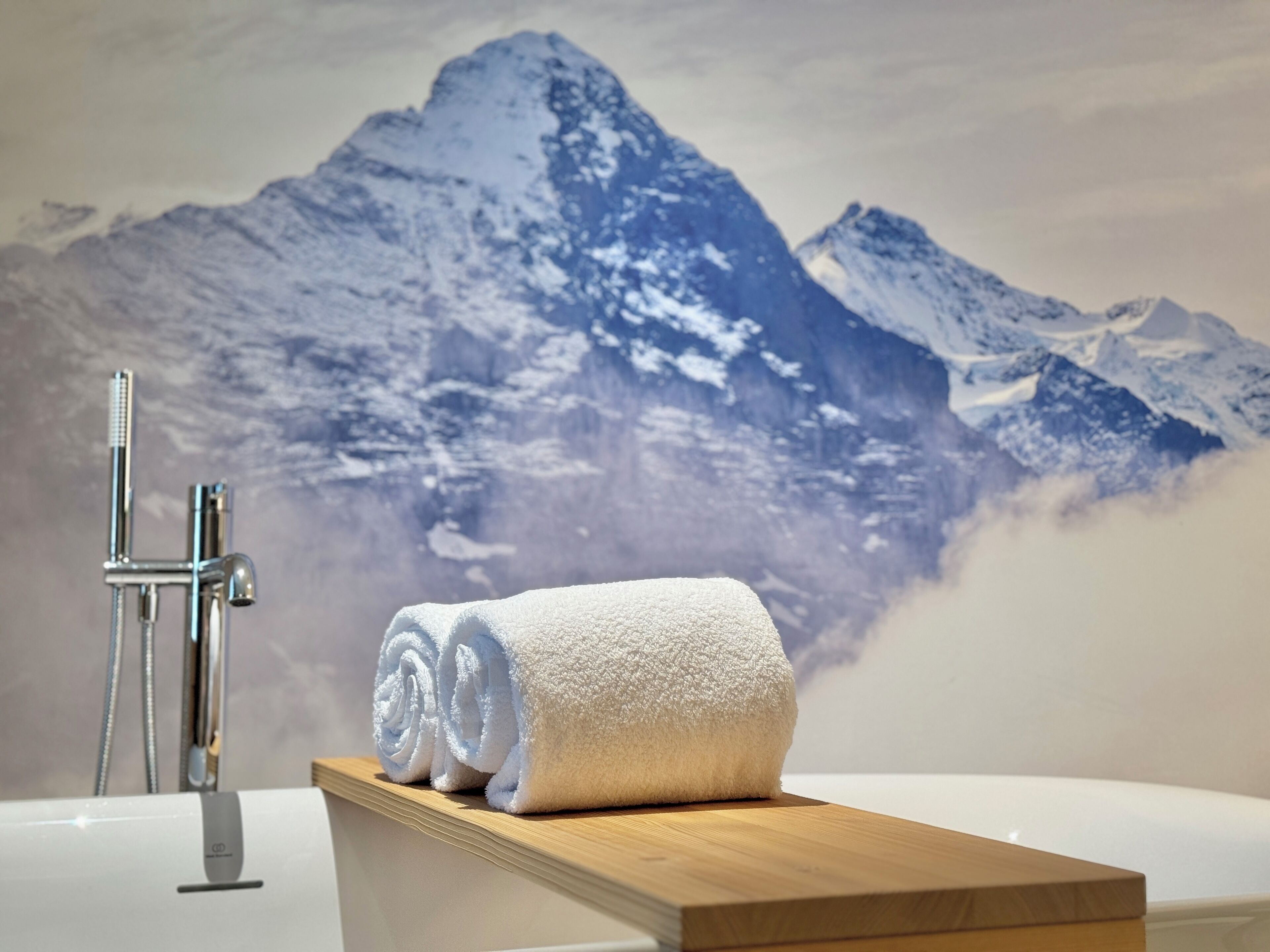 A bathroom with a wooden vanity, a white bathtub, and a towel.
