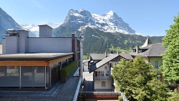 A modern building with a rooftop terrace overlooking a mountainous landscape.