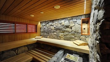 Eine Sauna mit Holzbänken, einer Steinwand und einer Holzbeschichtung.