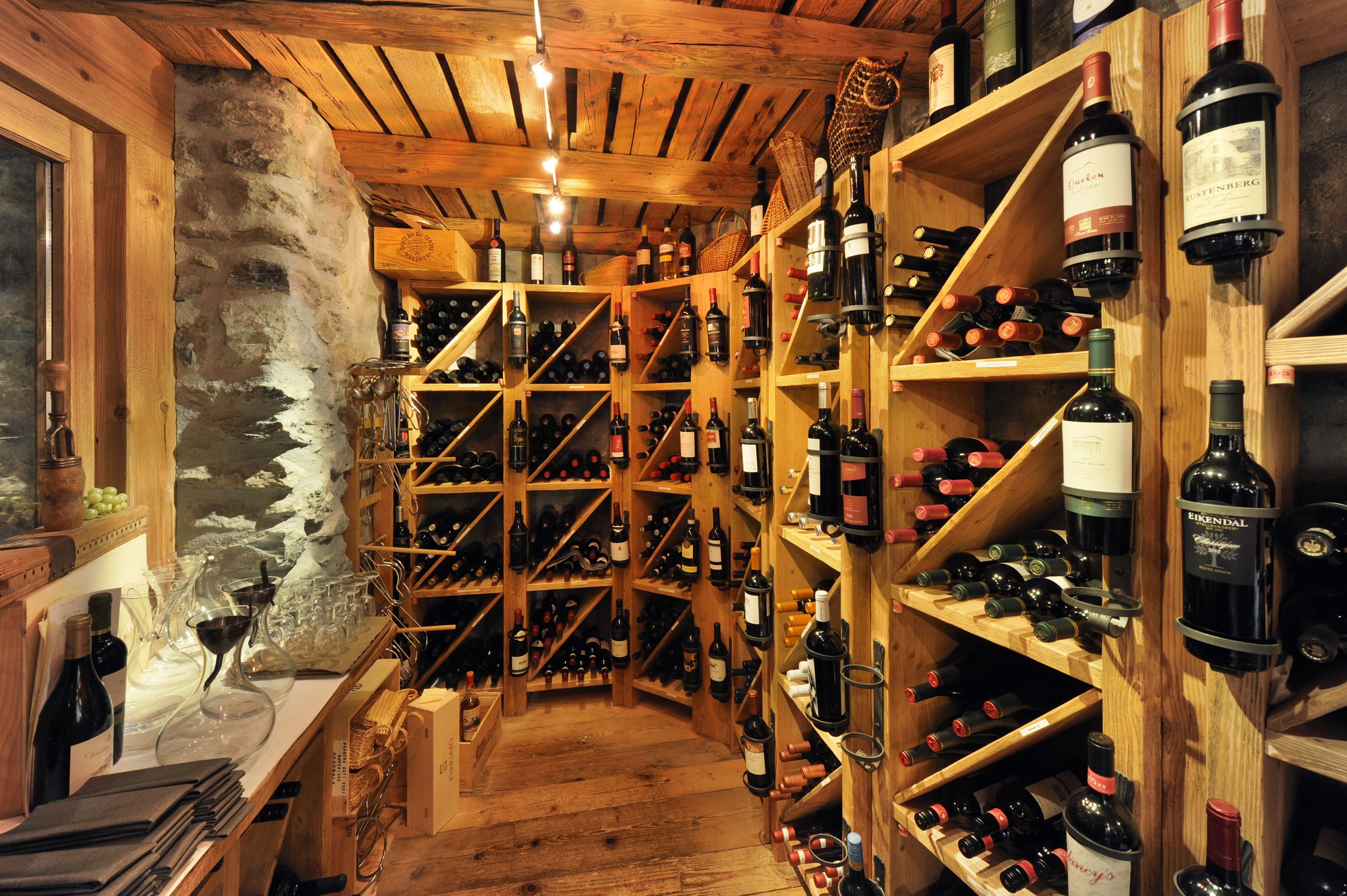 Une cave à vin avec des étagères et des supports en bois où sont rangées de nombreuses bouteilles de vin.