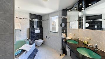 A modern bathroom with a bathtub, toilet, and two sinks.
