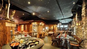 A restaurant with a buffet, wooden tables, and stone walls.