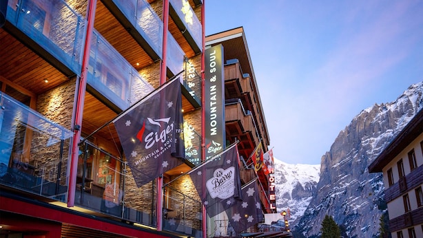 A hotel with multiple floors, large glass windows, and flags advertising nearby attractions.