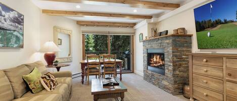 A cozy living room with a fireplace, a television, and a dining area with wooden furniture.