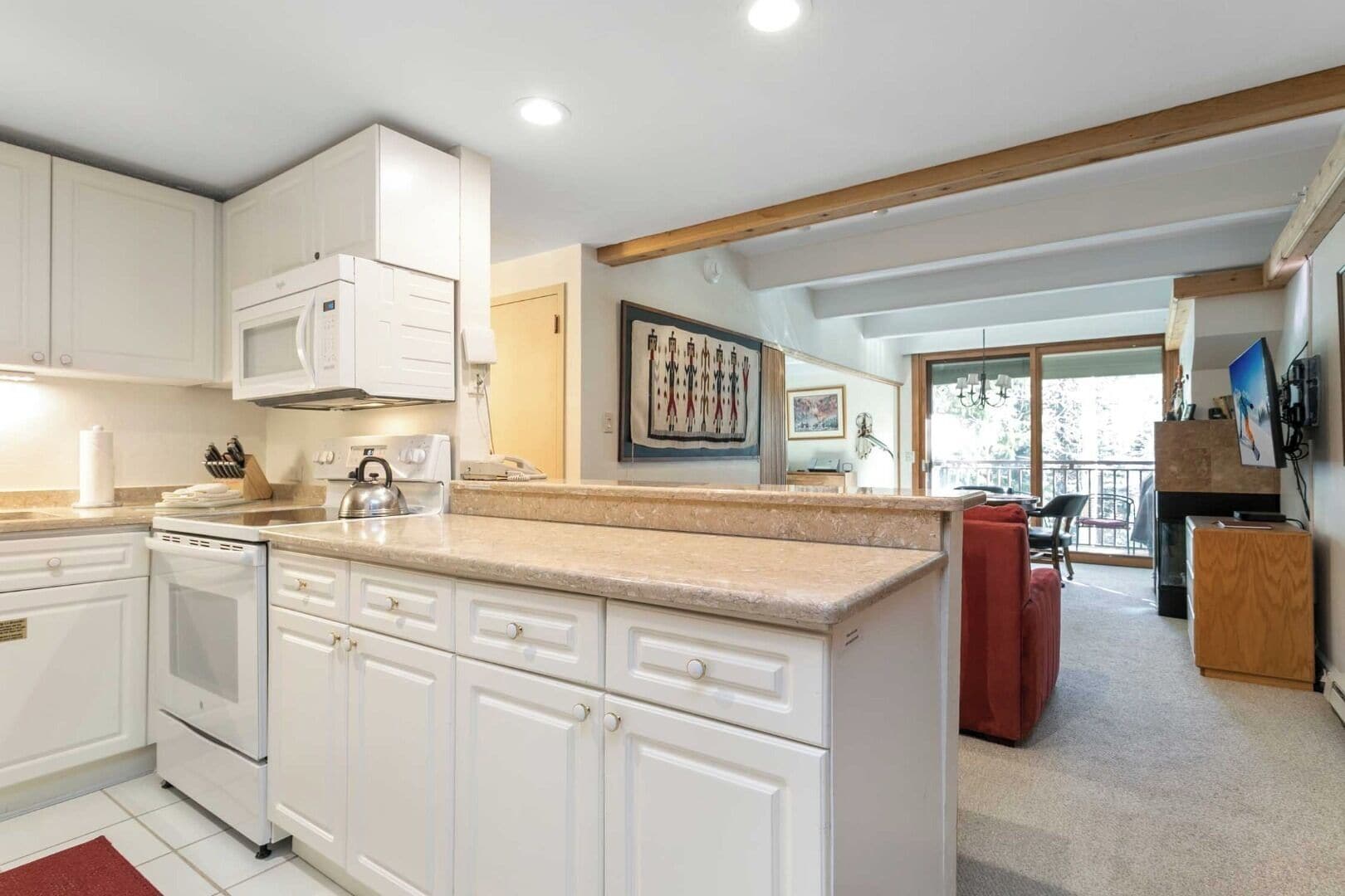 A modern kitchen with white cabinetry, a granite countertop, and a built-in microwave.