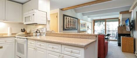 A modern kitchen with white cabinetry, a granite countertop, and a built-in microwave.