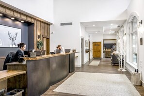 Zona de recepción con mostrador de madera, una obra de arte con cabeza de venado enmarcada y una recepcionista.