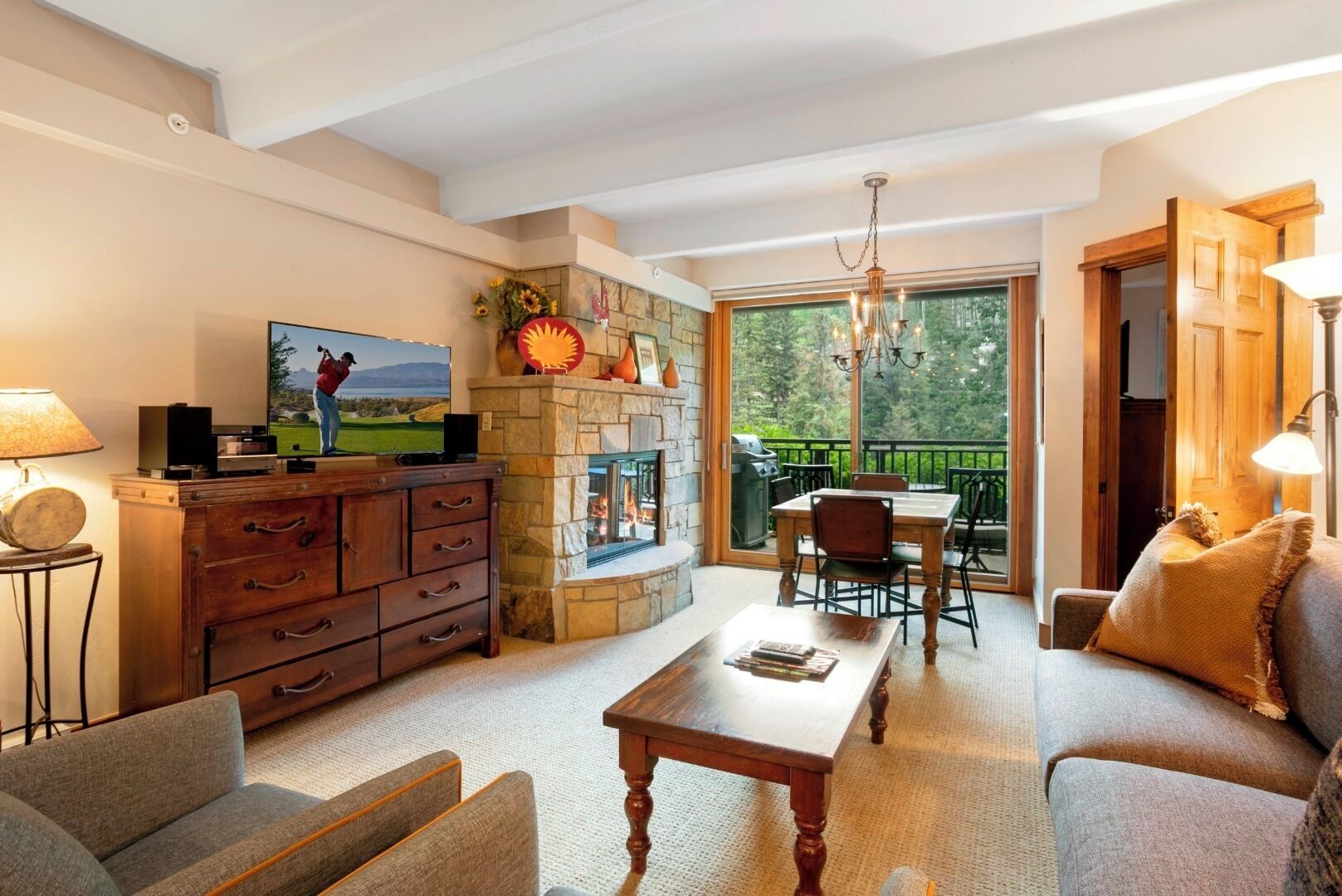 A spacious living room with a fireplace, a television, and a dining area with outdoor seating.
