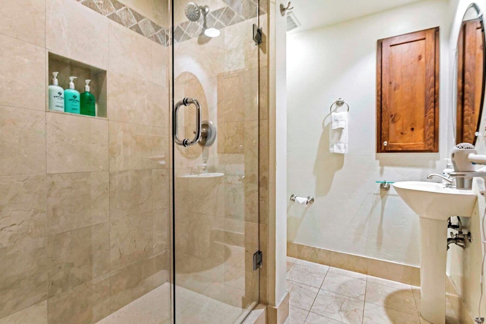 Une salle de bain moderne avec une douche à parois de verre, un lavabo et un meuble en bois.