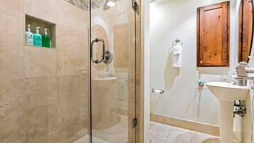 A modern bathroom with a glass-enclosed shower, a sink, and a wooden cabinet.