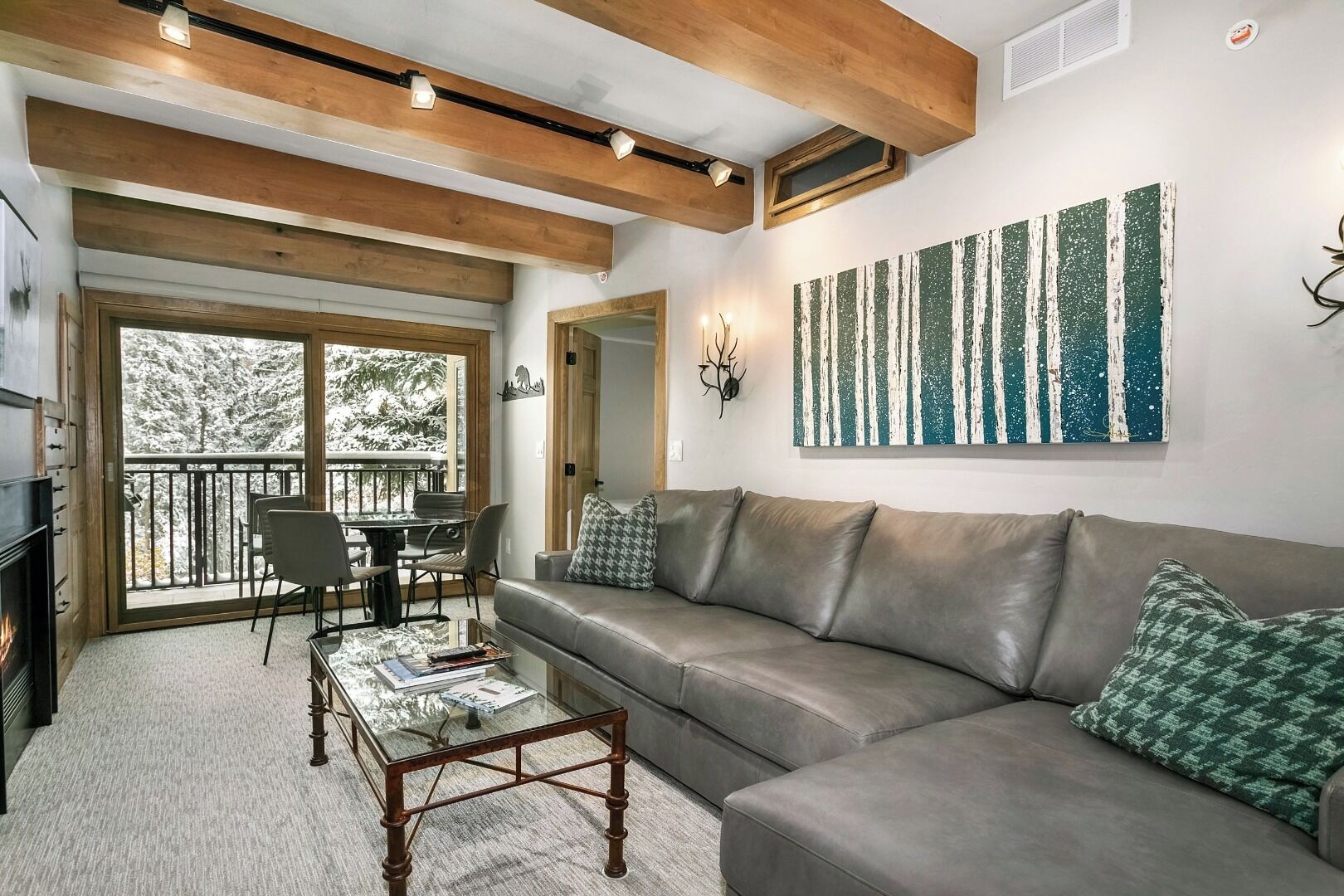 A cozy living room with a leather sofa, a glass coffee table, and a dining area with chairs.