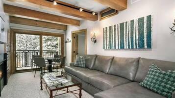 A cozy living room with a leather sofa, a glass coffee table, and a dining area with chairs.