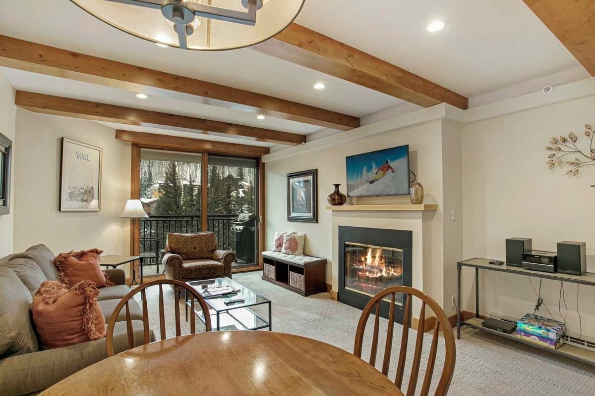 Una sala de estar acogedora con chimenea, vigas de madera, una mesa de comedor y un sofá.